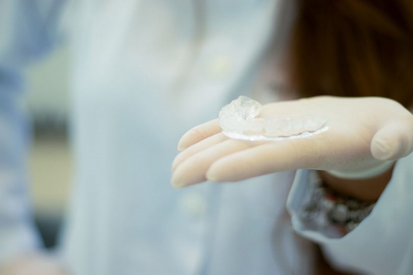Dentista avaliando alinhador invisível e planejamento ortodôntico digital em consultório