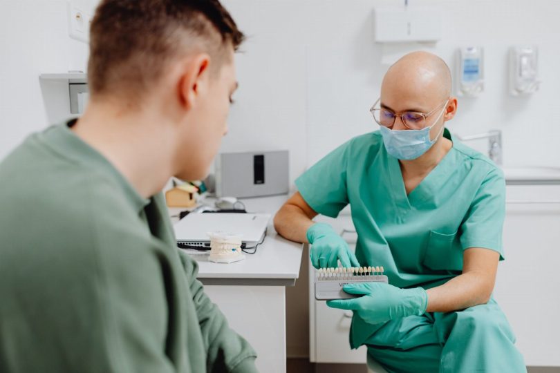 Dentista em consultório mostrando opções de clareamento dental a paciente