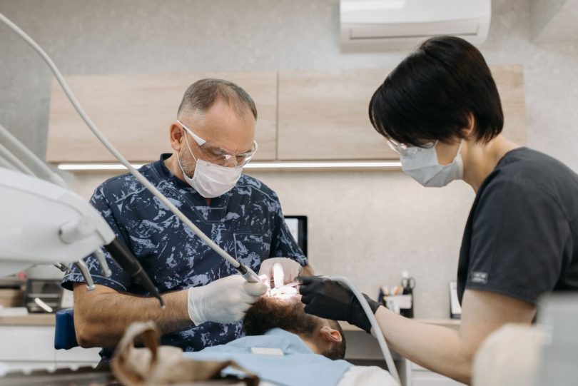 Dentista atendendo paciente em clínica odontológica com equipamento de endodontia