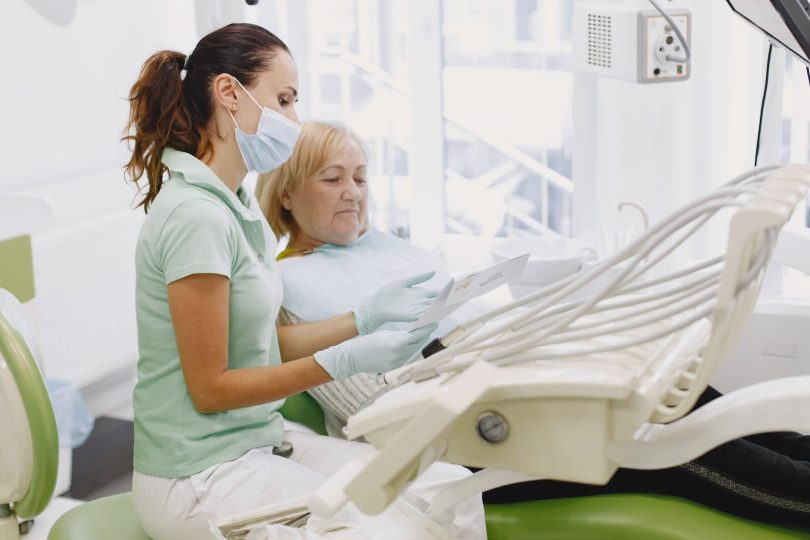 Dentista em consultório na Vila Mariana orientando paciente durante consulta com imagem radiográfica ao fundo