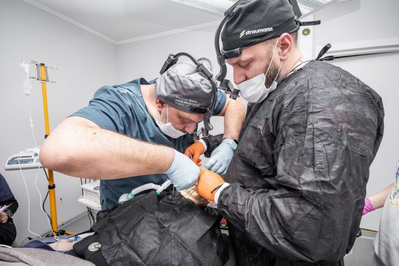 Dentista realizando ajuste e orientações de manutenção em implante dentário no consultório