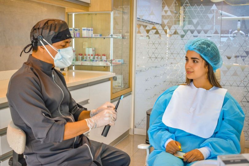 Dentista avaliando o sorriso do paciente e planejando facetas dentais com guia de cor e prontuário