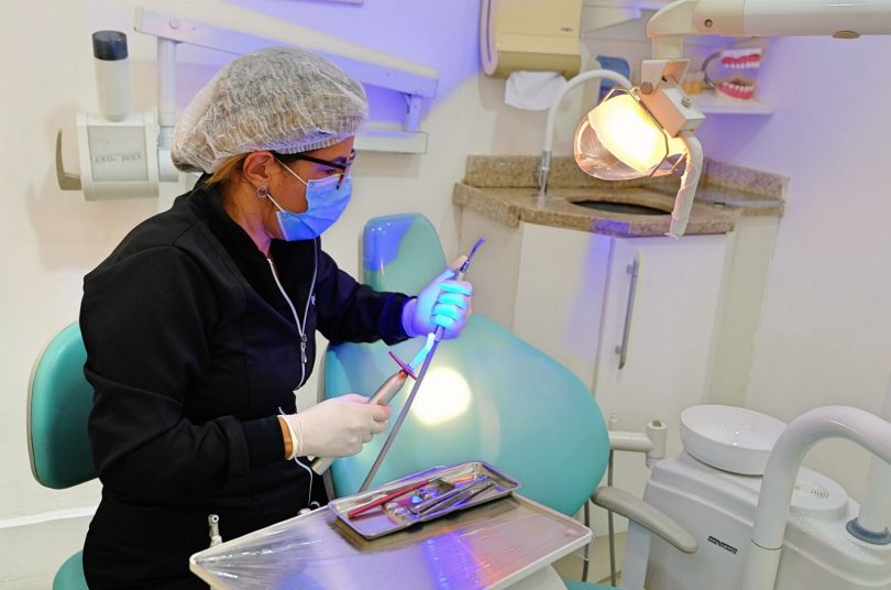 Dentista avaliando a cor dos dentes do paciente antes do clareamento dental em consultório odontológico
