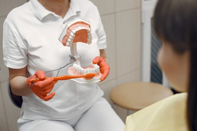 Dentista orientando paciente sobre escovação e cuidados para manter o sorriso saudável