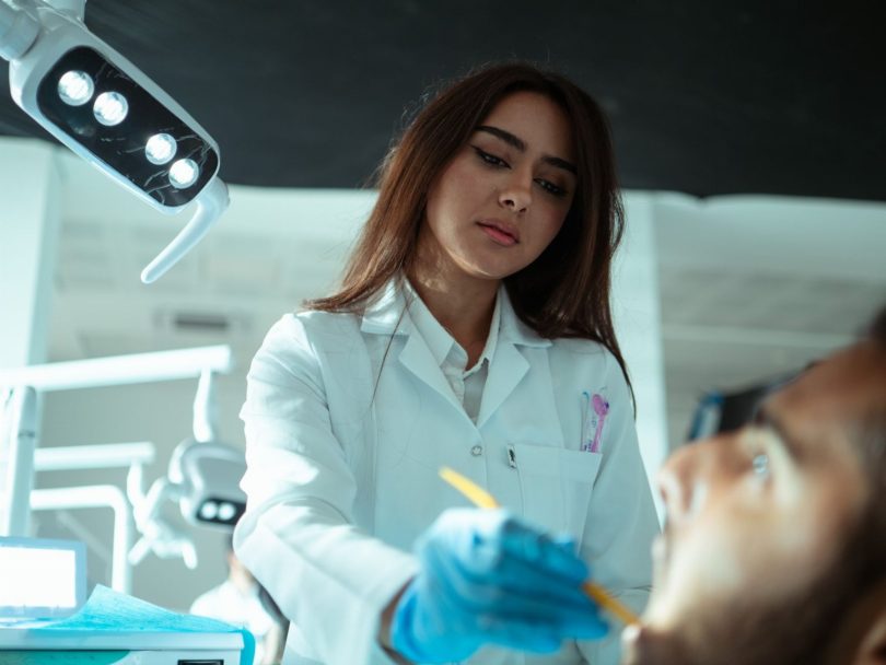 Dentista avaliando imagem radiográfica e sítio de enxerto ósseo no consultório