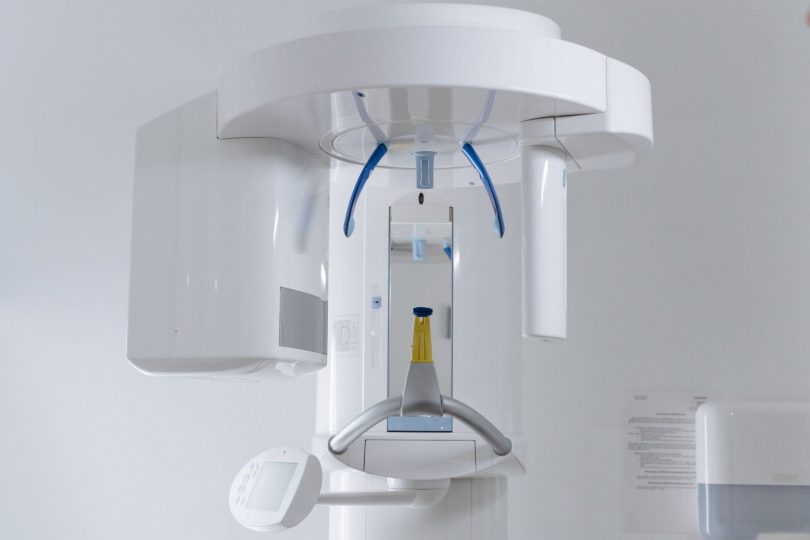 Paciente em cadeira odontológica com scanner intraoral sendo usado para planejamento de implante e prótese CAD/CAM