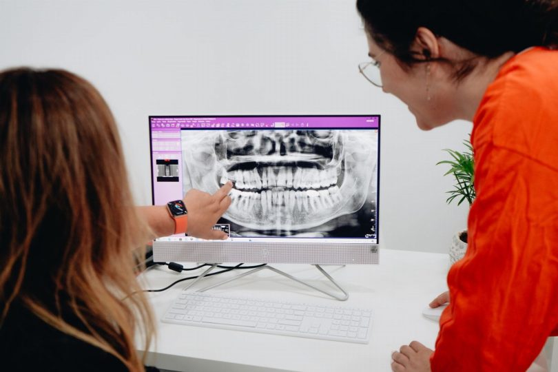 Dentista avaliando tomografia para planejamento de implante dentário em consultório odontológico na Vila Mariana