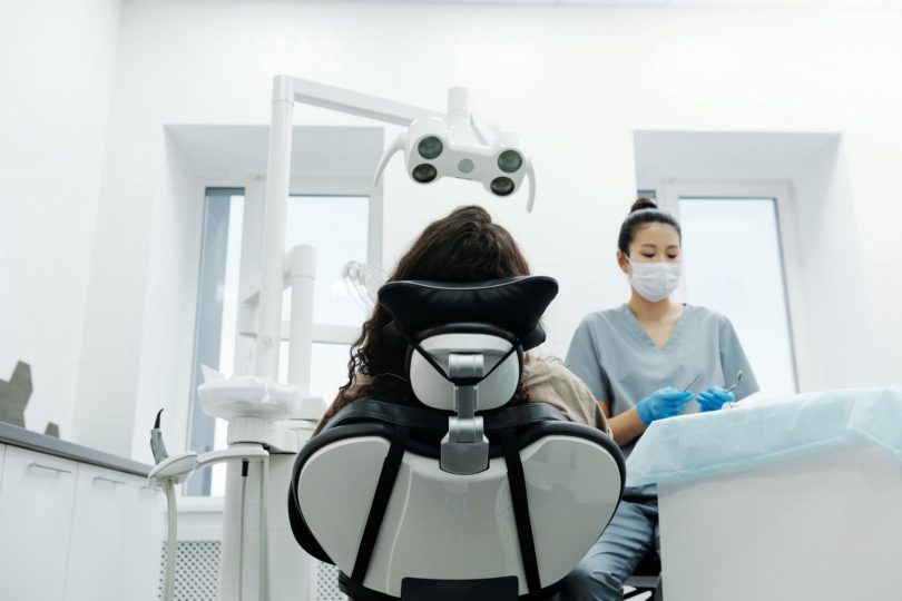 Paciente em cadeira odontológica recebendo explicação do dentista sobre implante dentário