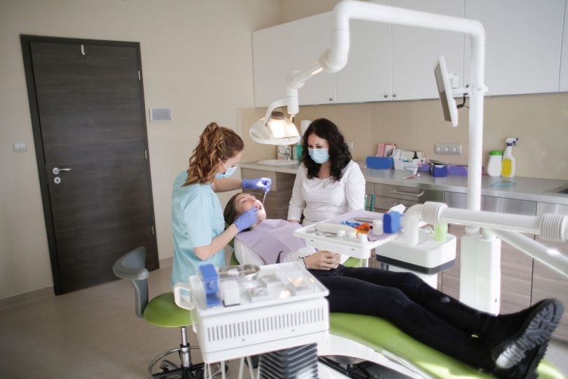 Dentista orienta paciente sobre higiene diária para manter lentes de contato dental com saúde gengival