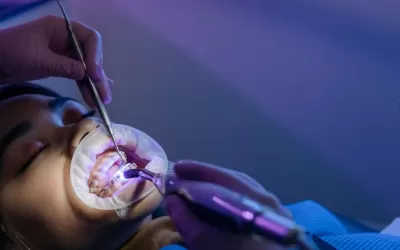 Ortodontista em consultório mostrando retentor ortodôntico removível e exemplo de contenção fixa para evitar que os dentes entortem novamente.