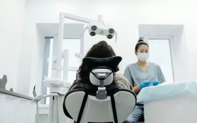 Paciente em cadeira odontológica recebendo explicação do dentista sobre implante dentário
